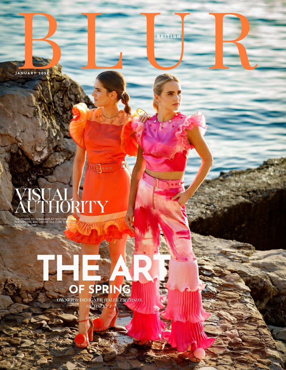 Magazine cover with two women in vibrant and colorful outfits by a body of water.